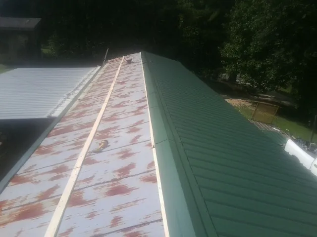 Old rusted panels beside newly installed green metal roofing — Wind Damage Roof Repair by Roofing Brothers in Shoup