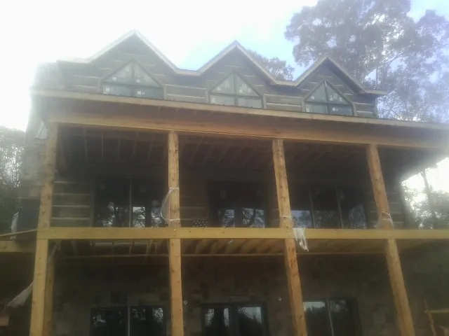 Dormers and porch framing on a large log home under construction — Roof Coating work by our crew in Shoup