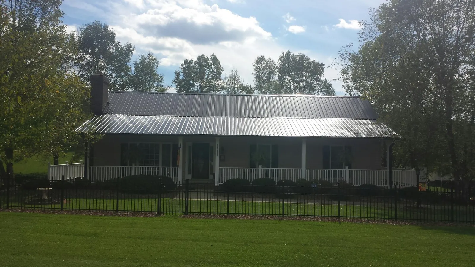 Gray metal roof on a brick ranch with a full width front porch — Gutter Guard Installation work by our crew in Shoup