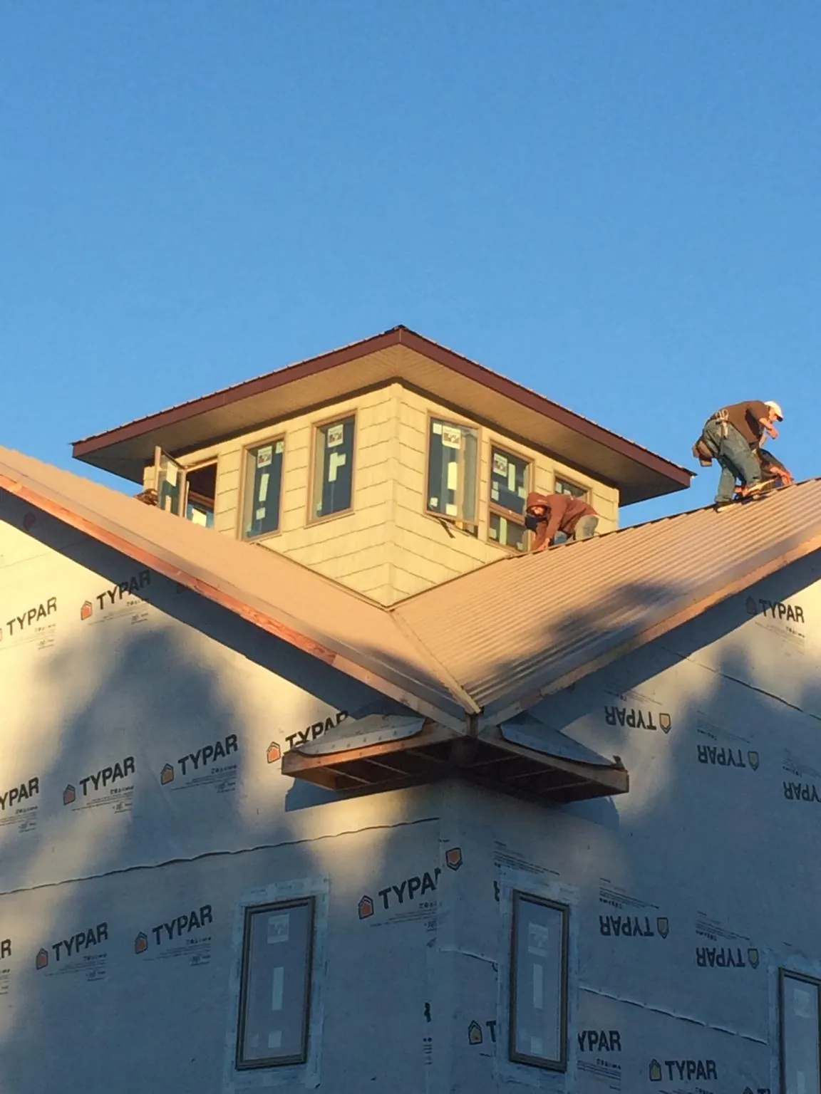 Roofers working around a rooftop cupola on a new metal roof at sunset — Roof Waterproofing in Shoup by Roofing Brothers